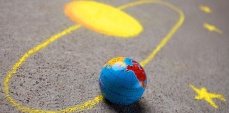 Mappamondo e sistema solare disegnato con un gessetto sull'asfalto