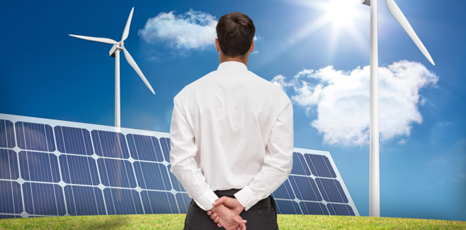 Uomo in piedi di fronte a pale eoliche e pannelli solari