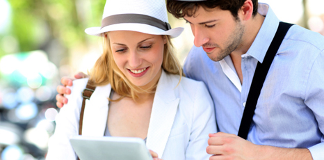 Una giovane coppia in vacanza guarda un tablet