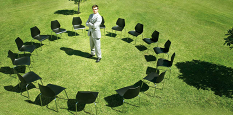 Sedie disposte a cerchio in un prato con al centro un docente in attesa dei partecipanti