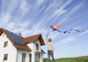 immagine di un ragazzo che gioca con un aquilone di fronte ad una casa con pannelli fotovoltaici