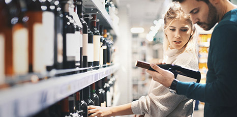 Due persone scelgono vino in un supermercato