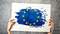 Due mani reggono un cartello con il disegno della bandiera dell'Unione Europea