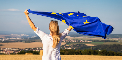Donna sventola la bandiera dell'Unione europea in mezzo alla campagna