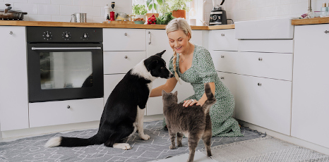 Una donna in cucina con un cane e un gatto